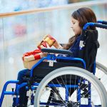 Side-view of disabled child in wheelchair looking at gift-box